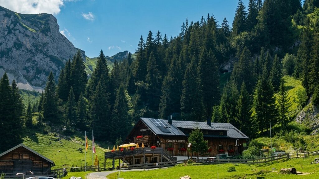Außenansicht der Füssener Hütte mit Holzfassade und Sonnenterrasse vor der Kulisse der Tannheimer Berge © Radio Alpenwelle CE2607