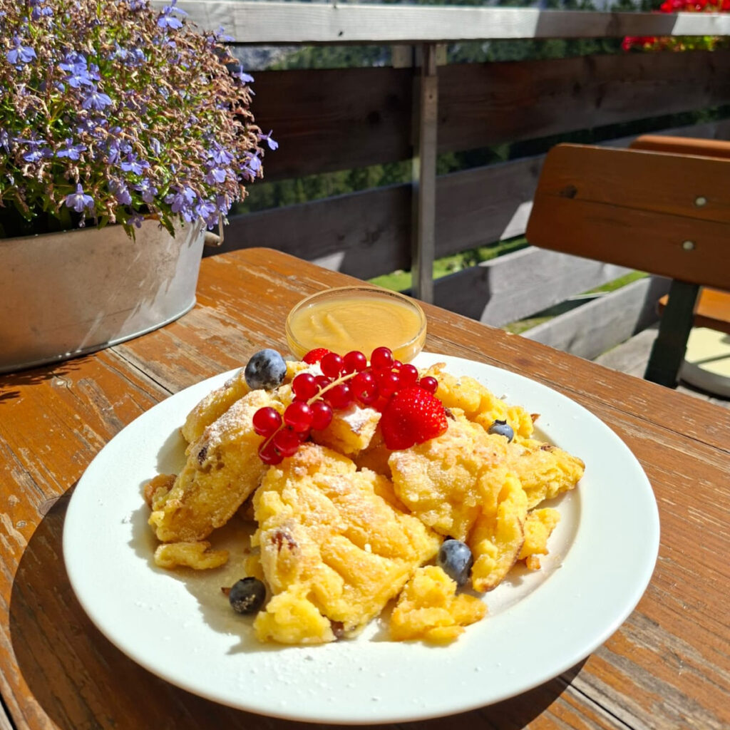 Ein Teller traditioneller Kaiserschmarrn mit Puderzucker und Johannesbeeren auf der Sonnenterrasse der Füssener Hütte, am Fuße der Tannheimer Alpen. © Radio Alpenwelle CE2607